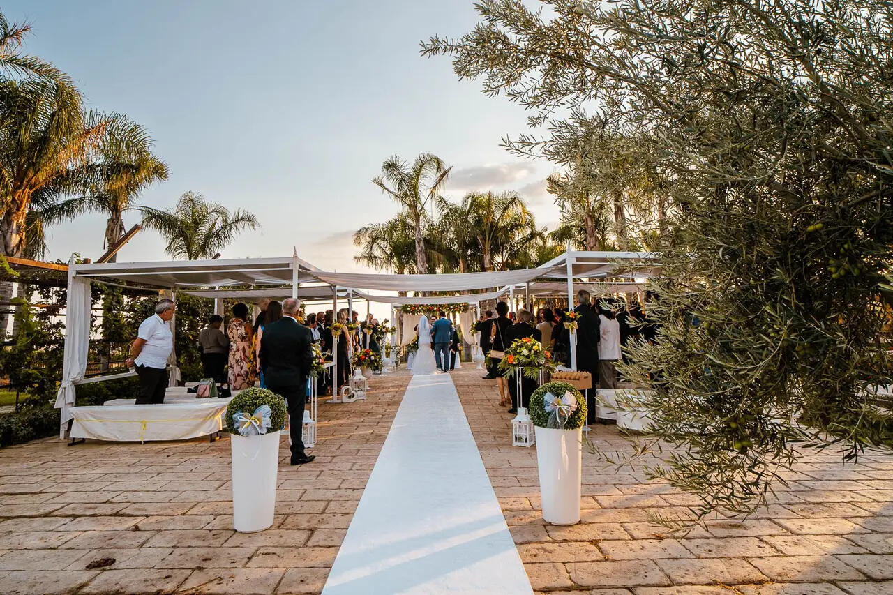 A wedding aisle running between white canopies at Villa Garufi, Biancavilla, palms and an olive tree either side