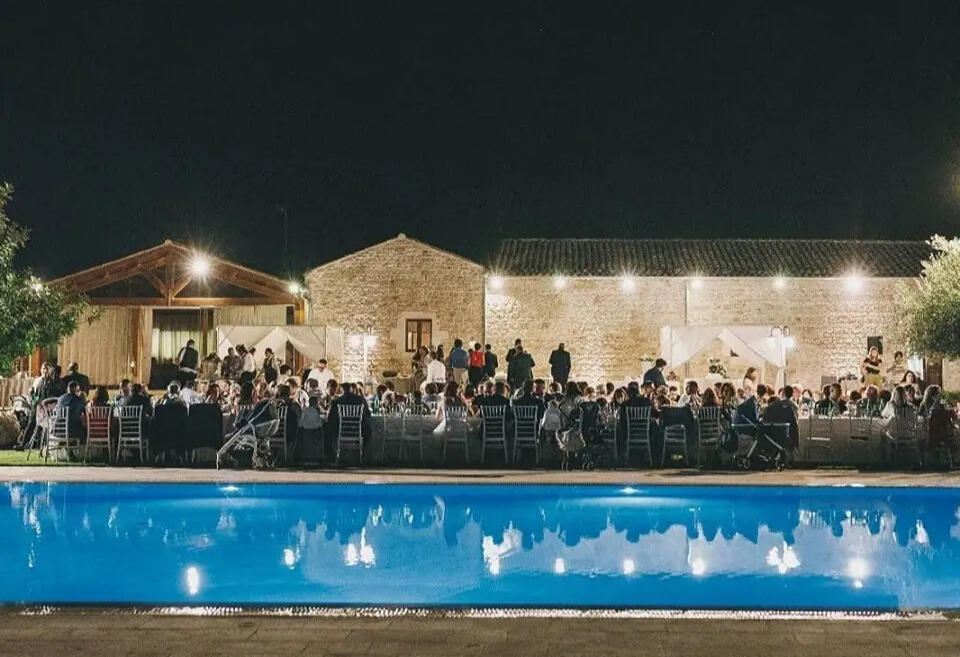 Dinner beside the pool at Casale Graffetta, Ispica, the lit stone casale behind the tables