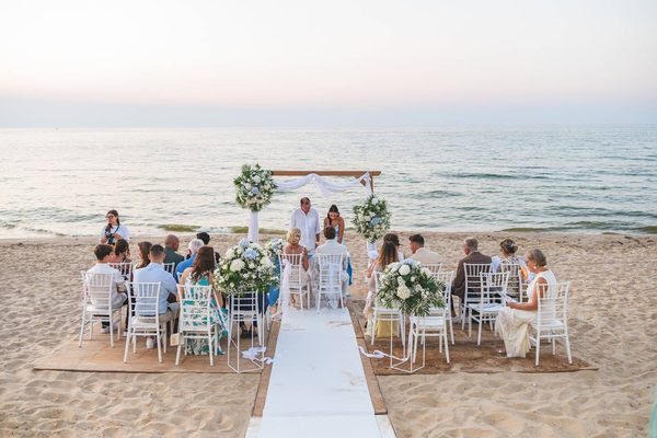 A ceremony on the sand at Alkamar, Alcamo Marina, the arch dressed with flowers and the sea behind